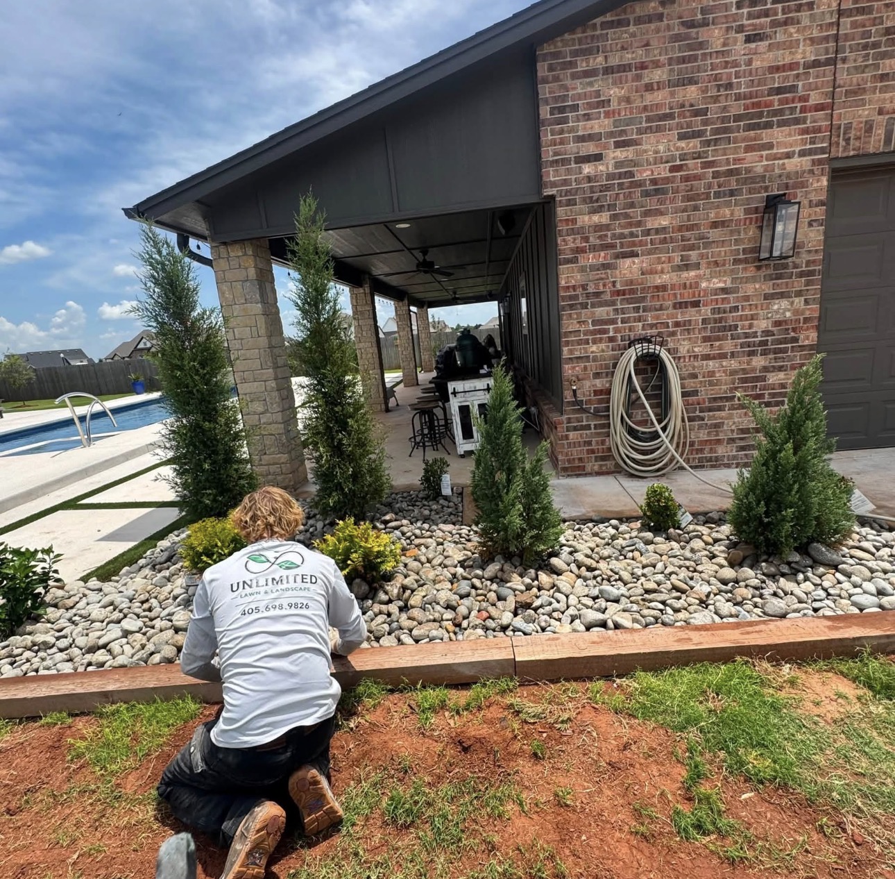 Unlimited Lawns & Landscape crew member setting plants in a rock bed